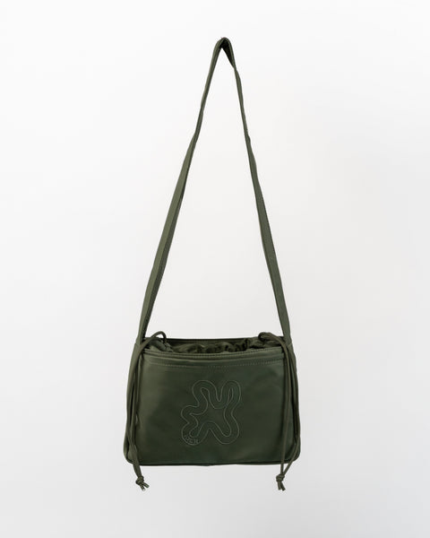 Green Shield Mini Crossbody, med snørelukning til at holde tasken kompakt. 