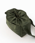 Green Shield Mini Crossbody set oppefra. Snørelukning med sløjfe. Broderet logo i samme grønne nuance. Frontlomme fra kant til kant.