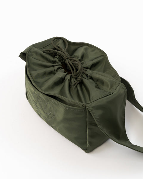 Green Shield Mini Crossbody set oppefra. Snørelukning med sløjfe. Broderet logo i samme grønne nuance. Frontlomme fra kant til kant.